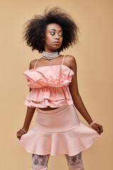 Young woman showcasing stylish pink outfit in a studio setting