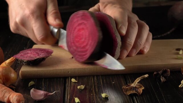 Hands chop a vibrant beet on a wooden board surrounded by fresh herbs and spices. The kitchen is warm and inviting, reflecting a love for cooking healthy meals.