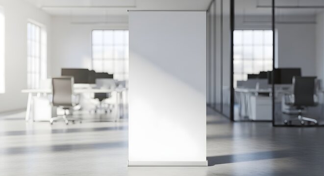 A blank white roll up banner stands in a modern office with desks and chairs visible