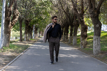 A man is walking down a tree-lined path