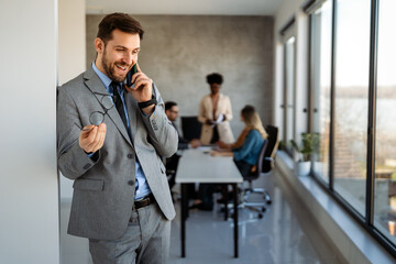 In a modern office, a successful businessman multitasks with phone communication