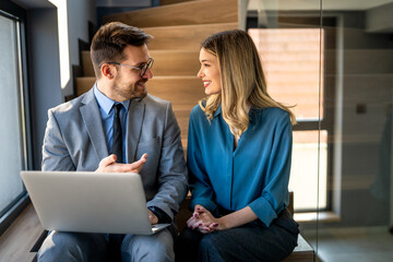 Two happy diverse multiethnic business team people working, talking in corporate office