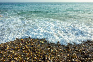 Ocean waves breaking on a beautiful pebble shoreline white foam bubbles turquoise water