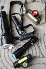 Set of various flashlights and headlamps on a surface. Ideal for ads on outdoor gear, camping...