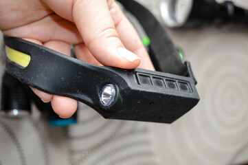 Hand holding a flexible LED headlamp strip with flashlights in the background. Great for ads on camping gear, wearable lighting, DIY tools, and outdoor safety.