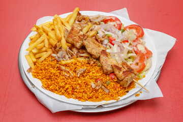 Assiette de chicken chika avec frites, salade et blé dur sur fond rouge, restauration rapide, halal