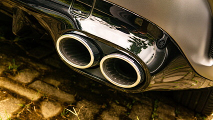 Dual chrome exhaust pipes with glowing rings on performance sports car detail