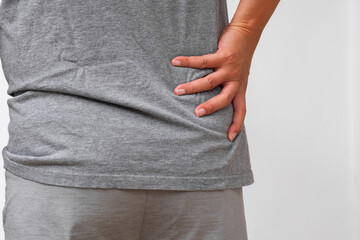 Asian man holding lower back—visible sign of hip or lumbar pain, muscle strain, or nerve tension. Ideal for spine care or orthopedic ads.