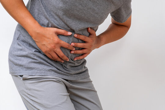 Asian man clutching abdomen—visible sign of internal organ pain, digestive disorder, or abdominal disease. Ideal for gastro or internal medicine ads. - Powered by Adobe