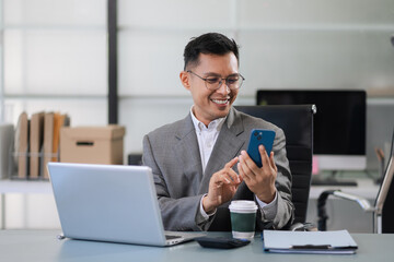 Businessman using smartphone and laptop computer in office. Happy man, entrepreneur, small business...