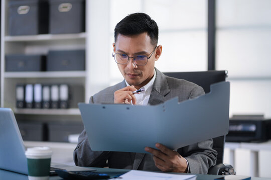 Business man working at office with laptop and documents on his desk, financial adviser analyzing data. - Powered by Adobe