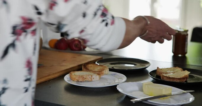 A mother preparing slices of fresh bread. A woman cuts fresh bread on a wooden board while preparing breakfast.
