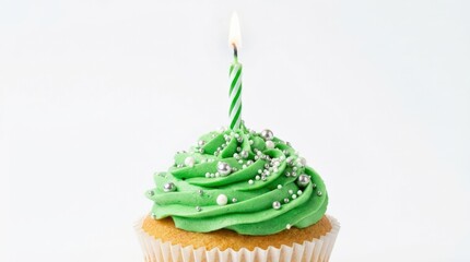 Festive cupcake with green frosting and a lit birthday candle on white