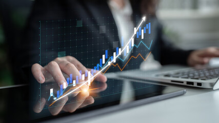 A business person examines financial data on a tablet, showcasing a digital chart that indicates a significant upward trend, symbolizing growth and success. Impute