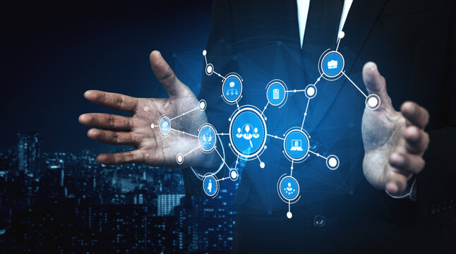 A businessman showcasing a futuristic digital network visualization, surrounded by symbols of technology and innovation over an urban cityscape at night. Tessel