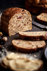 Rustic Christmas fruit bread filled with dried fruit, nuts and seeds, sliced and served on a dark textured surface. Ideal for festive, winter and holiday baking themes.