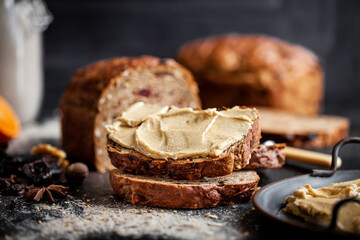 Rustic Christmas fruit bread filled with dried fruit, nuts and seeds, sliced and served on a dark textured surface. Ideal for festive, winter and holiday baking themes.