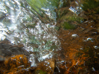 Abstract underwater closeup flowing stream over colorful stones nature background