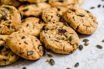 Golden muscovado sugar cookies studded with pumpkin seeds, arranged on a light textured surface. Ideal for baking themes, snack concepts and seasonal food content.