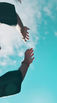 Graduation, below and students with cap in air for education success, milestone and achievement. University, high five and hands of friends throw for celebration, learning and applause on blue sky