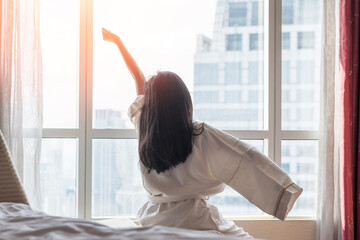 Hotel room comfort with good sleep easy relaxation lifestyle of Asian girl on bed have a nice day morning waking up, taking some rest, lazily relaxing in guest bedroom in city hotel