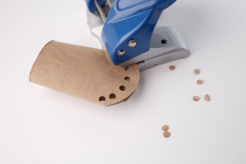 Manual hole puncher perforating cardboard for creative recycling, ideal for eco-friendly packaging,...
