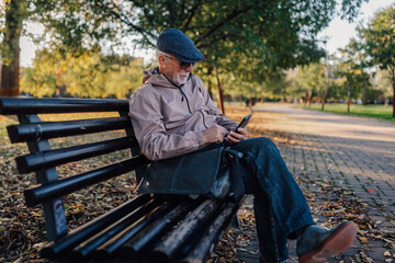 Senior man relaxing in park using smartphone