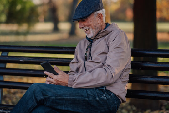 Senior man relaxing in park using smartphone