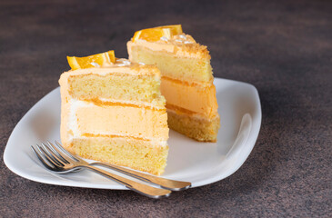 Two pieces of vanilla sponge cake with orange cream and mousse on white plate