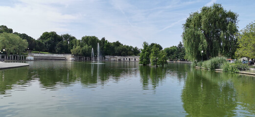 Calm lakeside view on a clear day with gentle ripples reflecting surrounding rocks and grassy shore