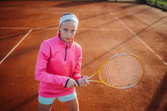 Young female tennis player holding racket on clay court