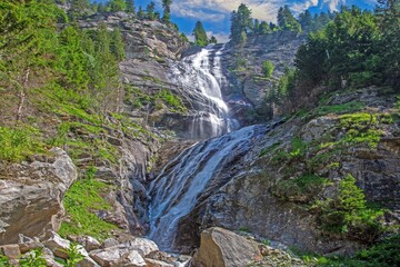Powerful alpine waterfall cascading down rocky cliff