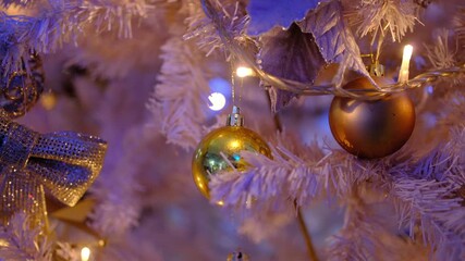 Golden christmas baubles and glowing fairy lights decorating a festive white artificial tree - Powered by Adobe
