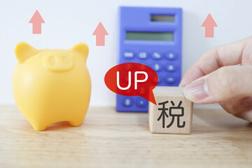 増税で家計負担が上昇するイメージ。貯金箱と税のブロック。