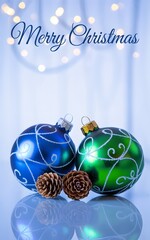Festive blue and green christmas ornaments with pinecones and blurred lights, holiday season greeting