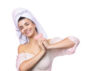 Beautiful cheerful attractive girl with a towel on her head, holds a sponge in the form of a pink heart.