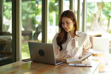 Woman studying with laptop and book at table.