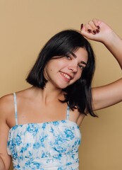 Fototapeta premium Smiling young woman in floral dress with cheerful expression against a plain yellow background