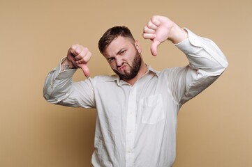 Man makes a disapproving gesture while wearing a white shirt against a neutral background