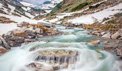 Alpine meltwater stream with smooth flowing water among rocks