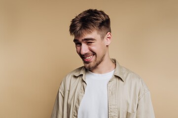 Joyful young man smiling in a light-colored shirt against a neutral background