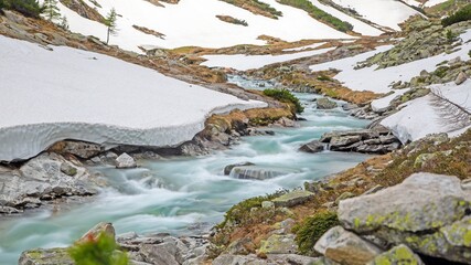 Alpine meltwater river winding through snowy mountain valley