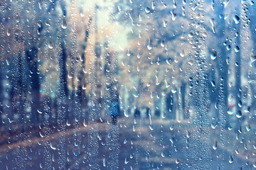 Obraz premium raindrops on glass blurred autumn background trees in the park, seasonal backdrop rainy weather