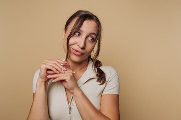 Woman playfully posing with a light smile against a neutral background during a casual indoor shoot