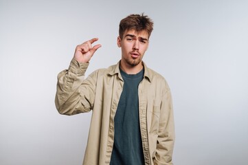 Man demonstrating a small size gesture in a casual outfit with a neutral background