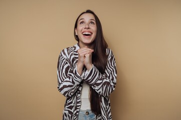 Woman smiling and expressing excitement, wearing striped jacket against a solid light background