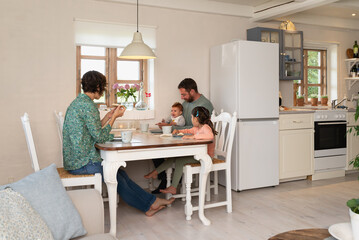 A family with their 5-year-old daughter and their 5-month-old baby enjoying their breakfast in their open-concept house with a rustic Danish style.