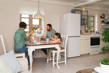 Baby begining her complementary feeding with baby-led weaning method during a family breakfast.
