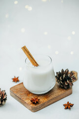 Creamy holiday drink with cinnamon stick and star anise on wooden board with pine cones © reddish