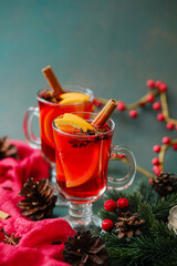 Two glasses of warm winter spice drink with orange slices and cinnamon sticks